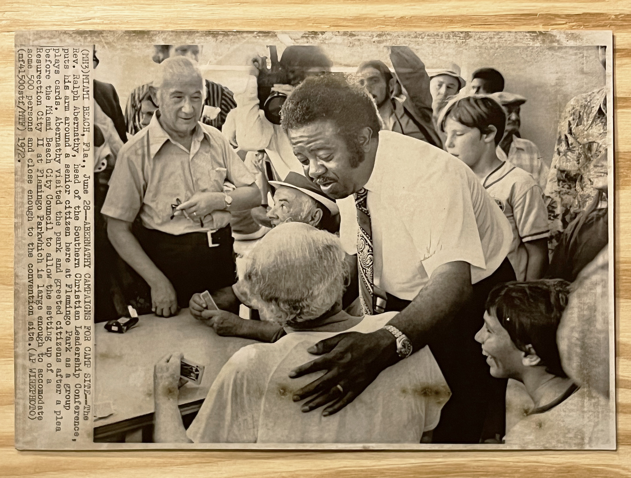 Found press photograph, caption reads:
MIAMI BEACH, Fla., June 28–ABERNETHY CAMPAIGNS FOR CAMP SITE–The Rev. Ralph Abernathy, head of the Southern Christian Leadership Conference, puts his arm around a senior citizen here at Flamingo Park as a group plays cards. Abernethy visited the park and greeted citizens after a plea before the Miami Beach City Council to allow the setting up of a Resurrection City II at Flamingo Park which is large enough to accomodate some 50 persons and close enough to the convention site. (AP WIREPHOTO) 1972.
